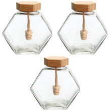 Glazen honingpot met houten lepel en deksel.