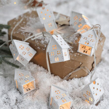Ghirlanda di luci natalizie a forma di casetta con decorazioni in legno, perfette per allestimenti festivi e composizioni floreali stagionali.