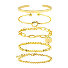 Conjunto de pulseras apilables con letras doradas, monedas y cuentas en forma de corazón.