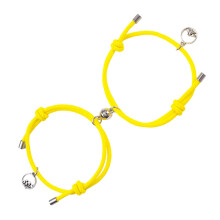 Bracelet tressé ajustable pour couple avec clochette magnétique en acier inoxydable, symbolisant l'attraction mutuelle et reliant les cœurs.