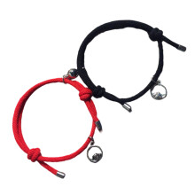 Bracelet tressé ajustable pour couple avec clochette magnétique en acier inoxydable, symbolisant l'attraction mutuelle et reliant les cœurs.