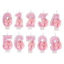 Roze strikjes als cijferkaarsen voor de taartdecoratie van een babymeisje voor haar verjaardag