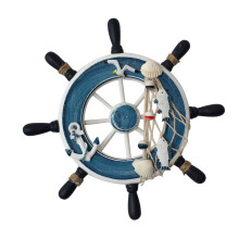 Wanddecoratie van een houten scheepswiel met touw en schelpen.