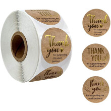 Adesivos de agradecimento em papel kraft marrom, 500 unidades por rolo, com detalhes em dourado.