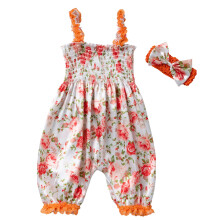 Macacão infantil com estampa floral e laço de renda.
