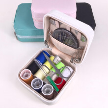 Naaisetje in een witte etui met naalden, garen, schaar en plakband.
