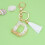 Beige nyckelring med initial och vit tofs 1