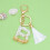 Beige nyckelring med initial och vit tofs 1