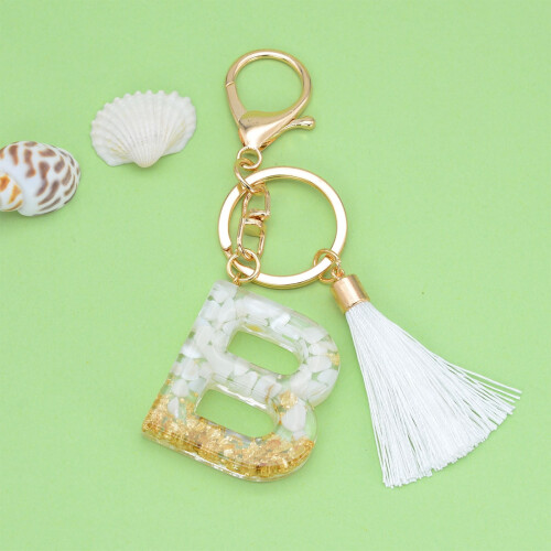Beige nyckelring med initial och vit tofs